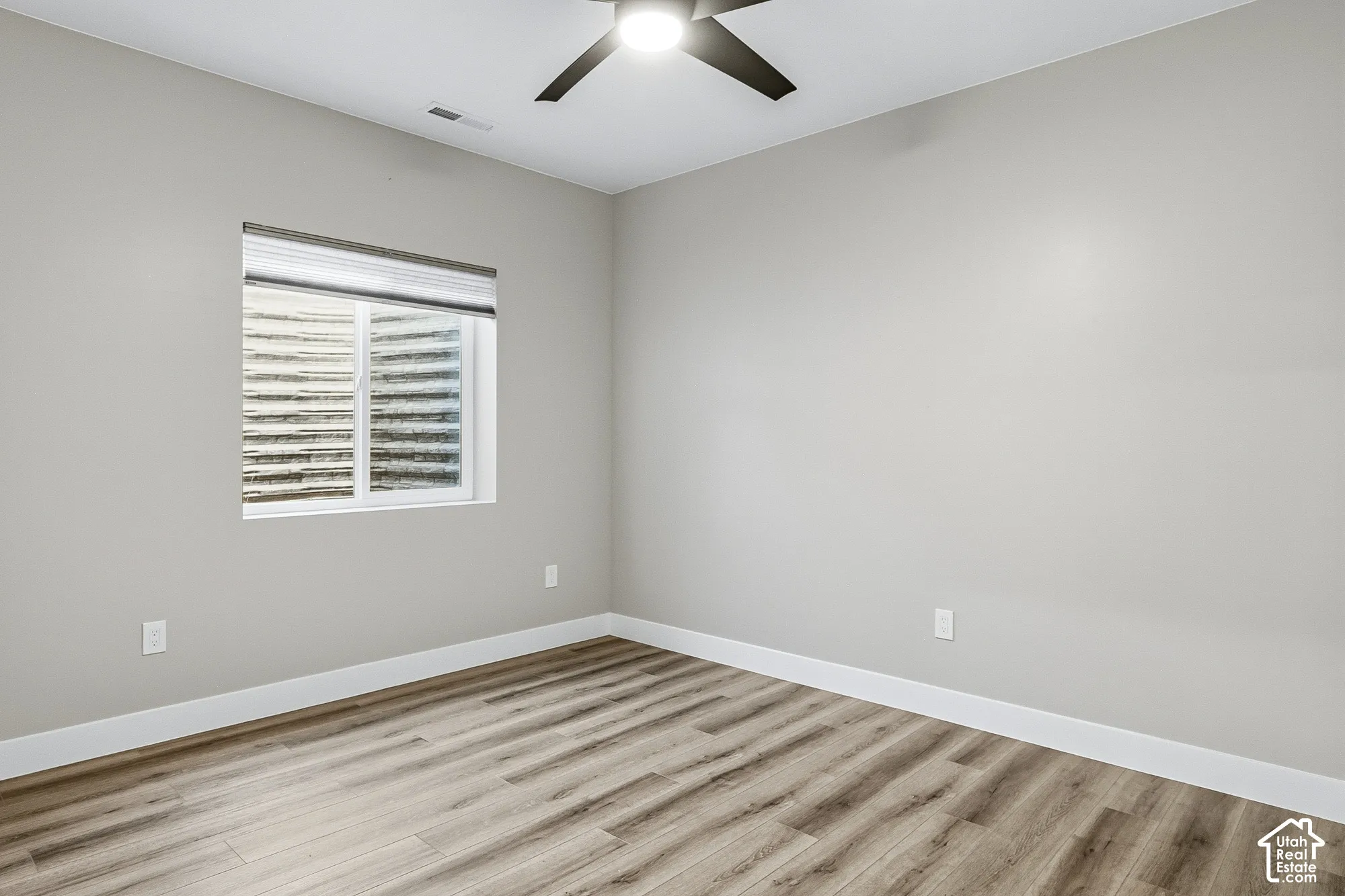 Recessed window with white blinds, wood-finish flooring, light gray wall paint, and a ceiling fan with integrated lighting
