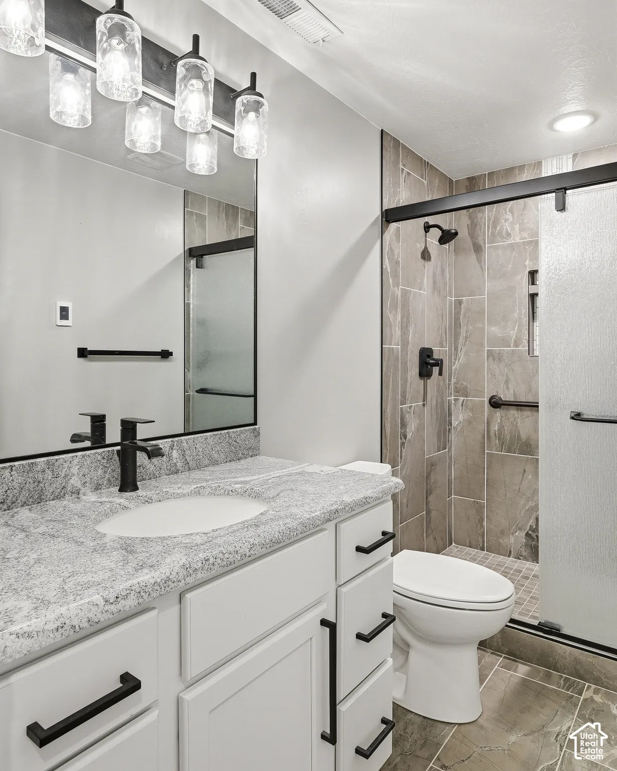 White vanity with a stone-finish countertop, undermount sink, and matte black faucet