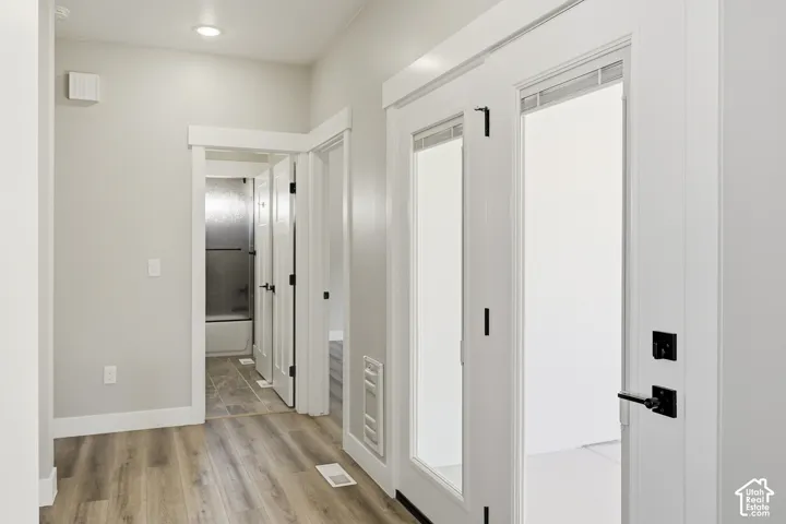 Wood-finish flooring throughout, bright white walls, recessed ceiling lighting, and matte black door hardware