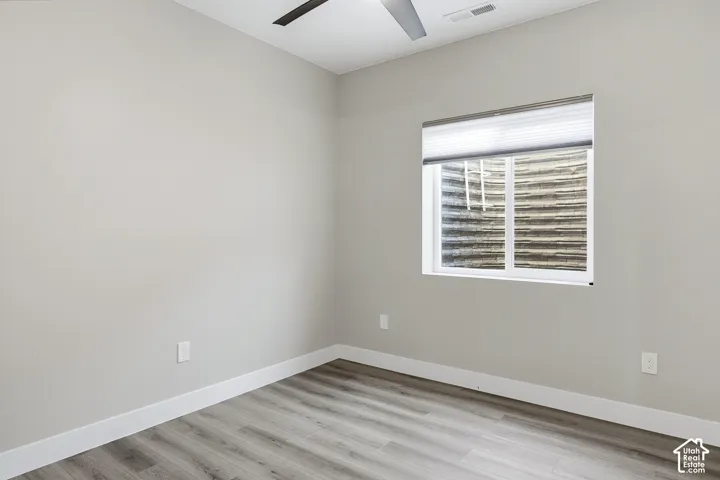 Neutral wall color, wood-finish flooring, white trim, ceiling fan, window with privacy blinds