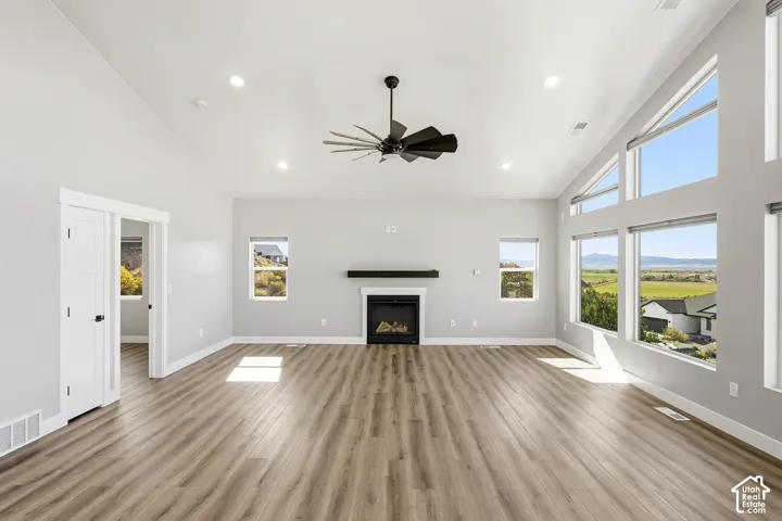 Vaulted ceiling with recessed lighting, wood-finish flooring, and a fireplace with a dark mantel