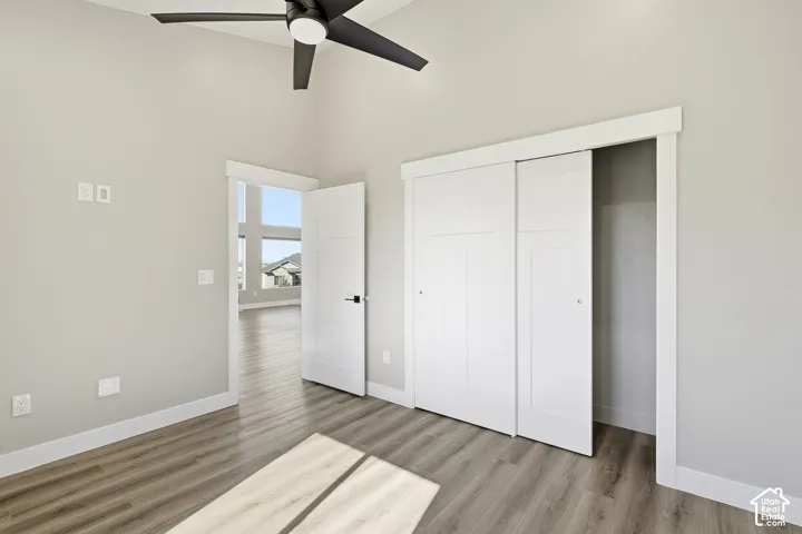 Vaulted ceiling with a ceiling fan, wood-finish flooring, white sliding closet doors, and a solid core door
