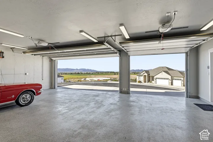 Two-car garage with overhead doors, an epoxy-coated concrete floor, and fluorescent overhead lighting