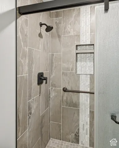 Shower with large format stone-finish wall tile, decorative vertical accent tile, a built-in shower niche, and a contrasting shower floor tile