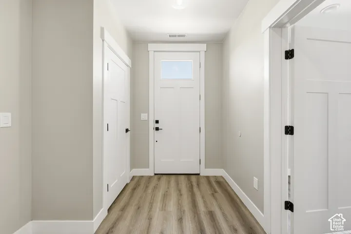 Wood-finish flooring with white trim and a recessed ceiling light