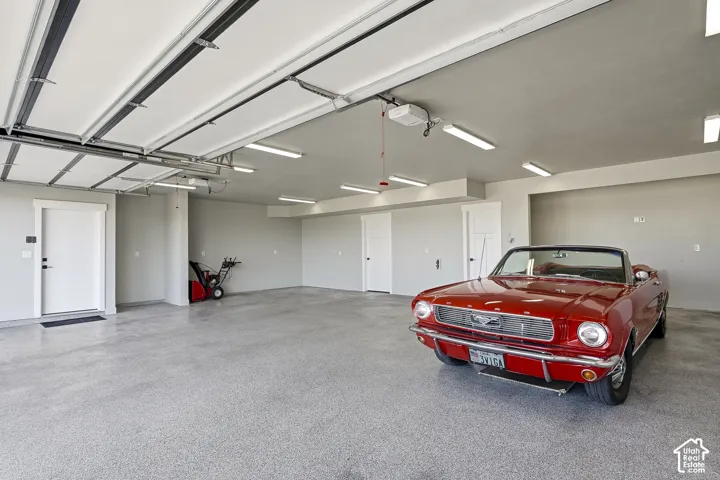 Spacious garage with an epoxy-coated concrete floor, multiple fluorescent light fixtures, and a white insulated garage door