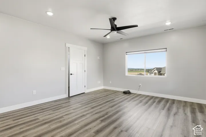 Laminate wood-finish flooring, recessed lighting, and a contemporary ceiling fan