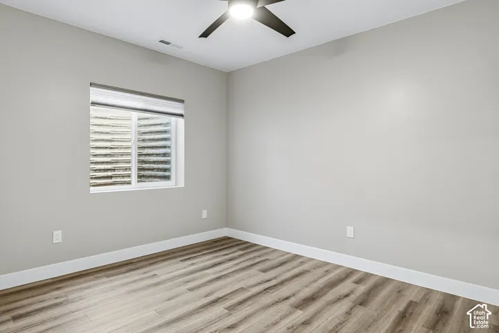Recessed window with white blinds, wood-finish flooring, light gray wall paint, and a ceiling fan with integrated lighting