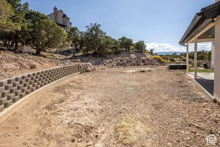Expansive property featuring a concrete block retaining wall and a covered patio area