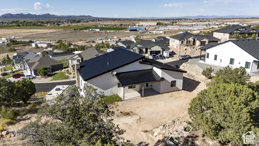 Modern design with a dark metal roof, light-colored stucco exterior, and covered patio