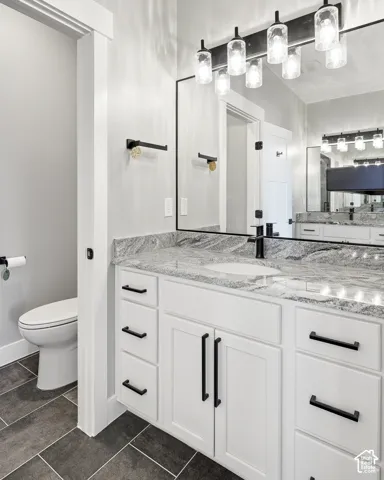 White vanity with sleek black hardware, granite countertop, undermount sink with a black faucet, and a large rectangular mirror