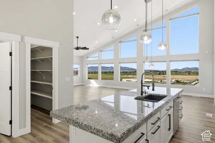 Kitchen island with a light-toned countertop, black sink, and modern pendant lighting