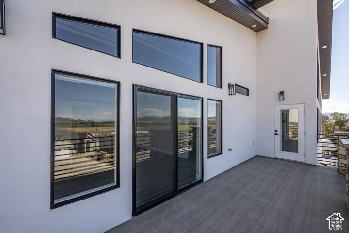 Expansive outdoor deck with composite flooring, featuring multiple windows, a glass-paneled door, and a sliding glass door