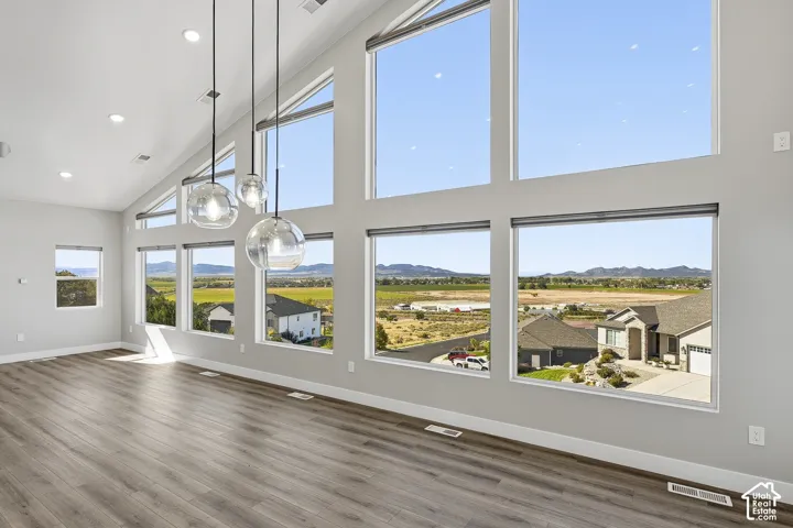 Vaulted ceiling with recessed lighting, large picture windows, wood-finish flooring, and modern pendant light fixtures