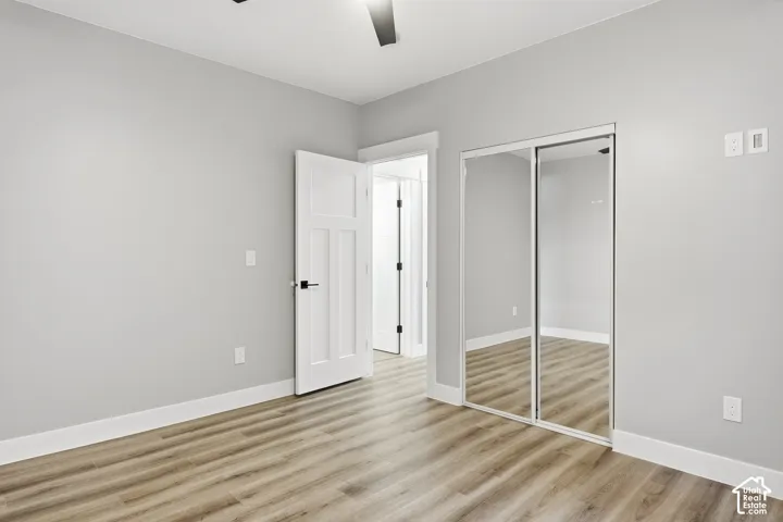 Wood-finish flooring, white paneled door with black hardware, and mirrored closet doors
