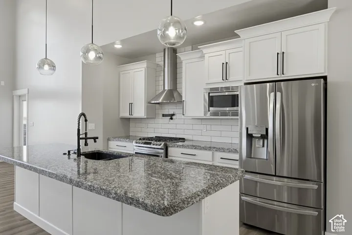 Kitchen featuring a granite-top island with an undermount sink, white cabinetry with dark hardware, stainless steel appliances, and a subway tile backsplash