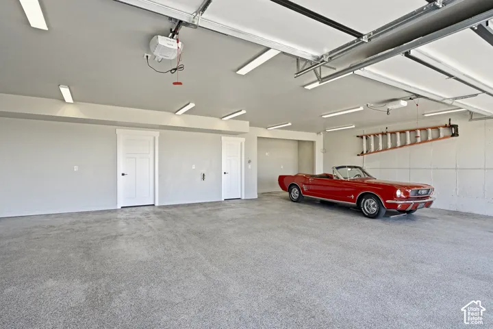 Spacious garage featuring a finished floor, multiple overhead lights, and two interior access doors with dark hardware
