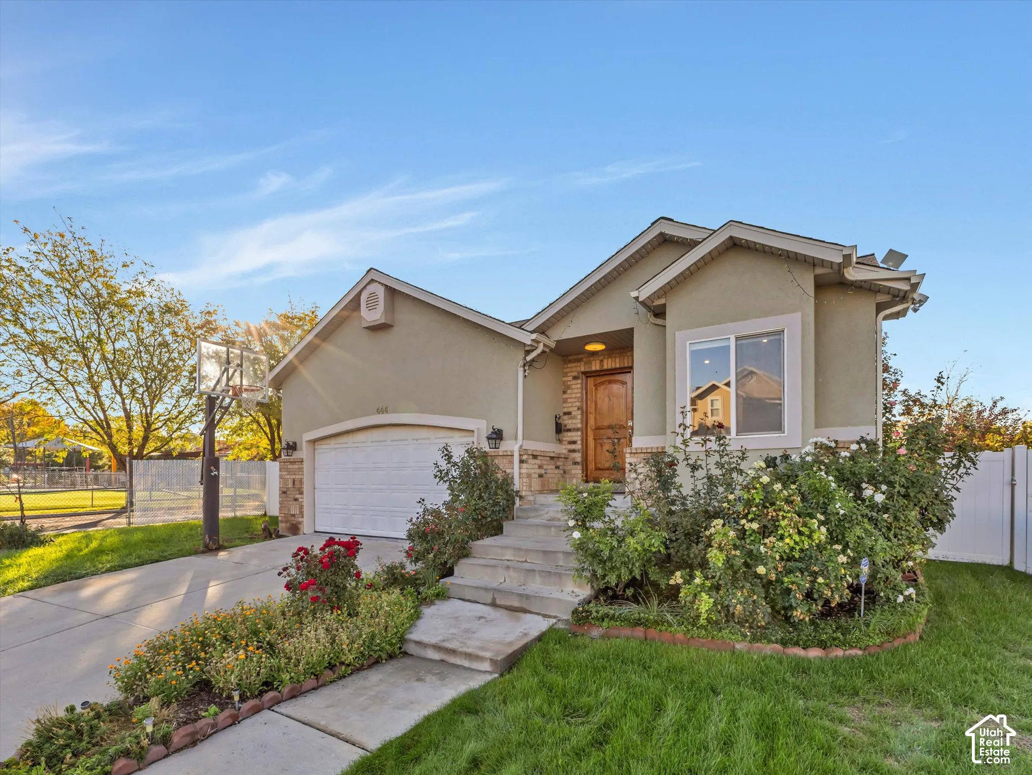 Stucco exterior with stone accents, integrated garage, concrete driveway, and established landscaping