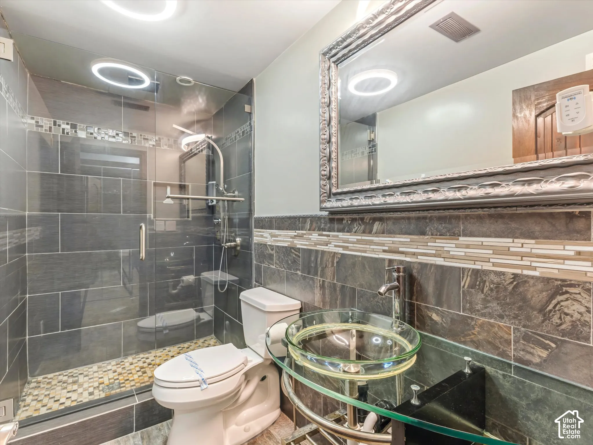 Glass-enclosed shower with pebble-tile flooring and dark stone-look wall tiles