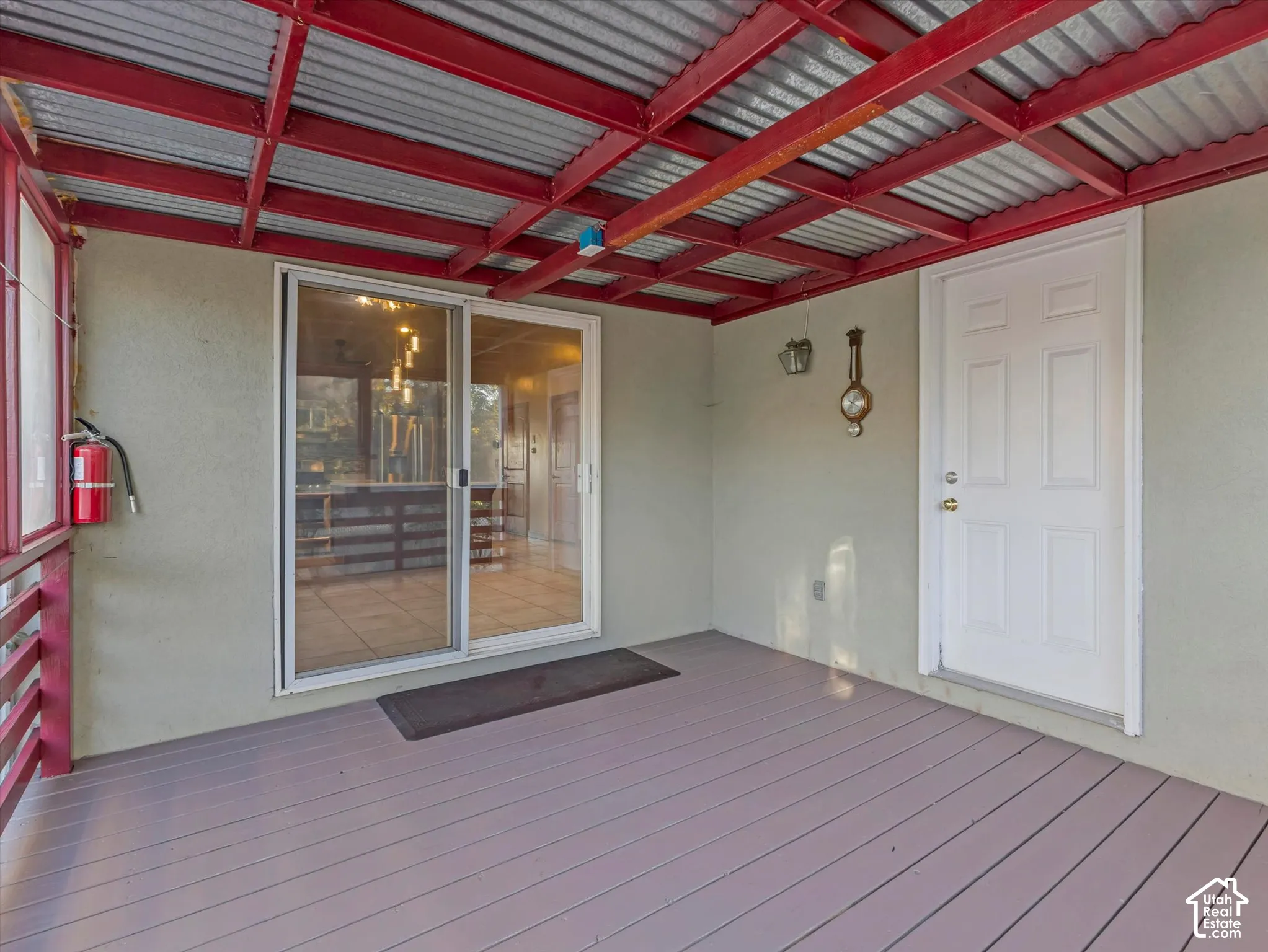 Covered outdoor deck with a corrugated metal ceiling and exposed red structural beams