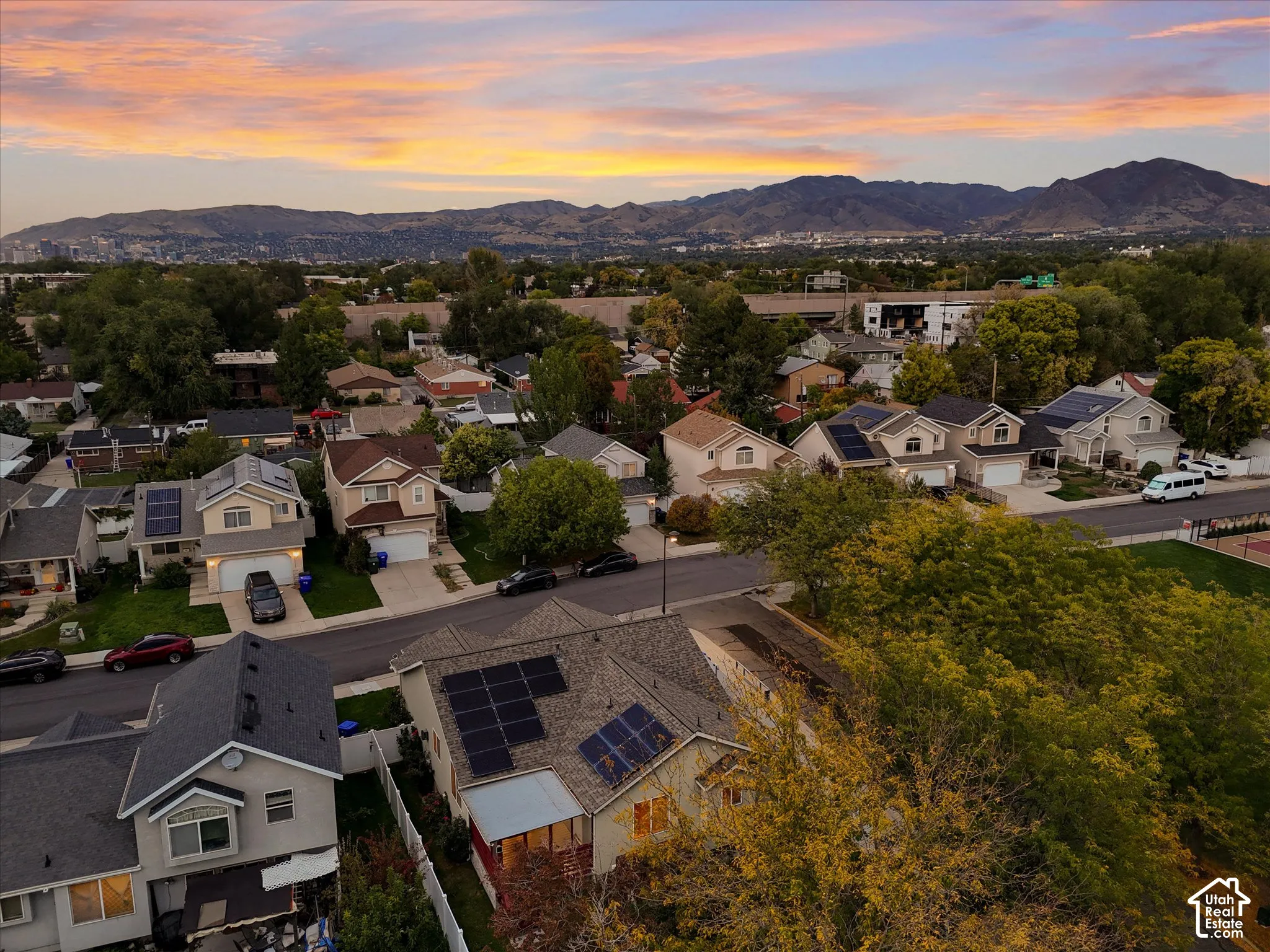 Neighborhood setting featuring varied residential structures, mature landscaping, and mountain backdrop