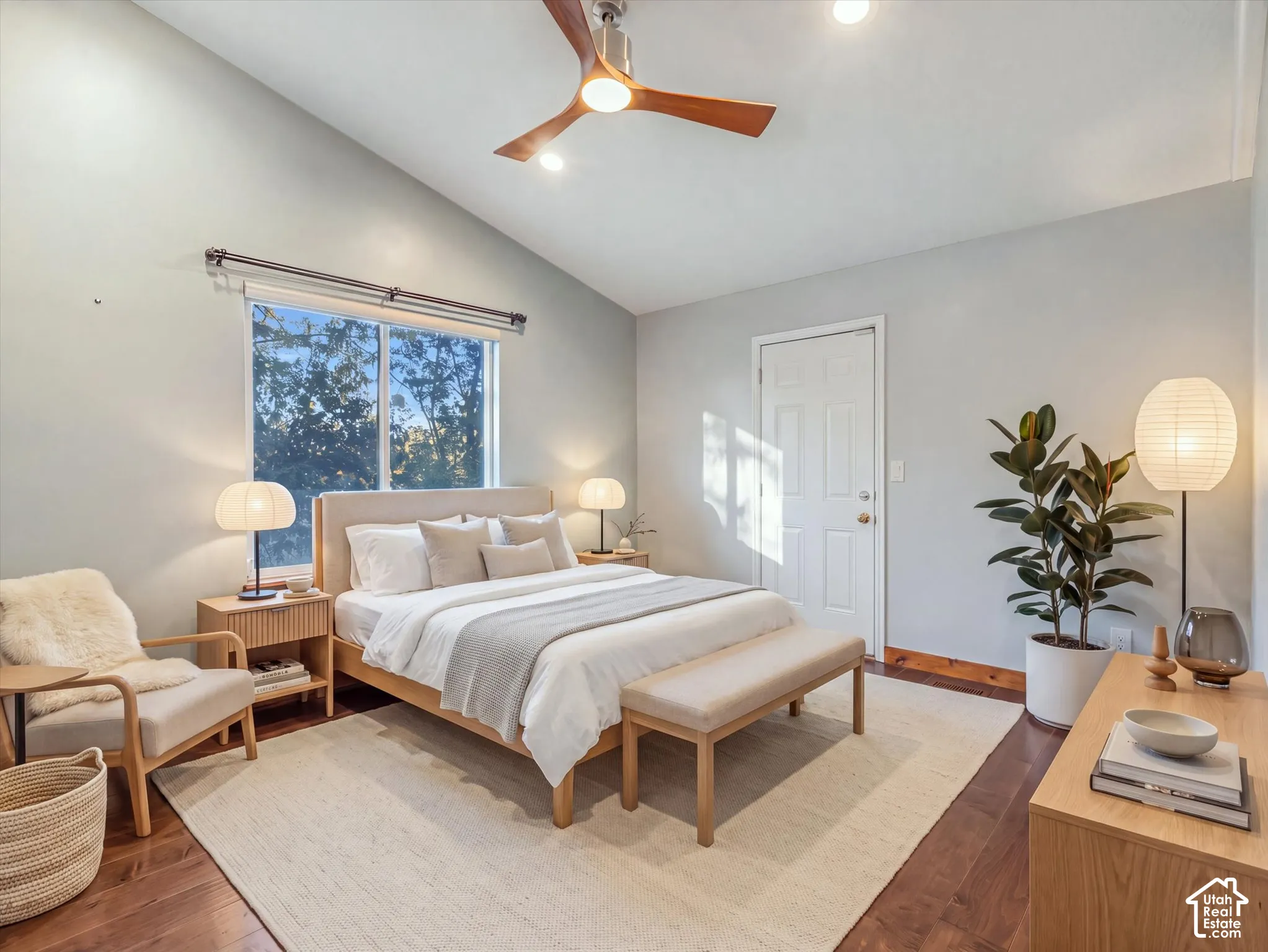 Vaulted ceiling with a wood-finish ceiling fan, wood-finish flooring, and a large window.Digitally Staged.