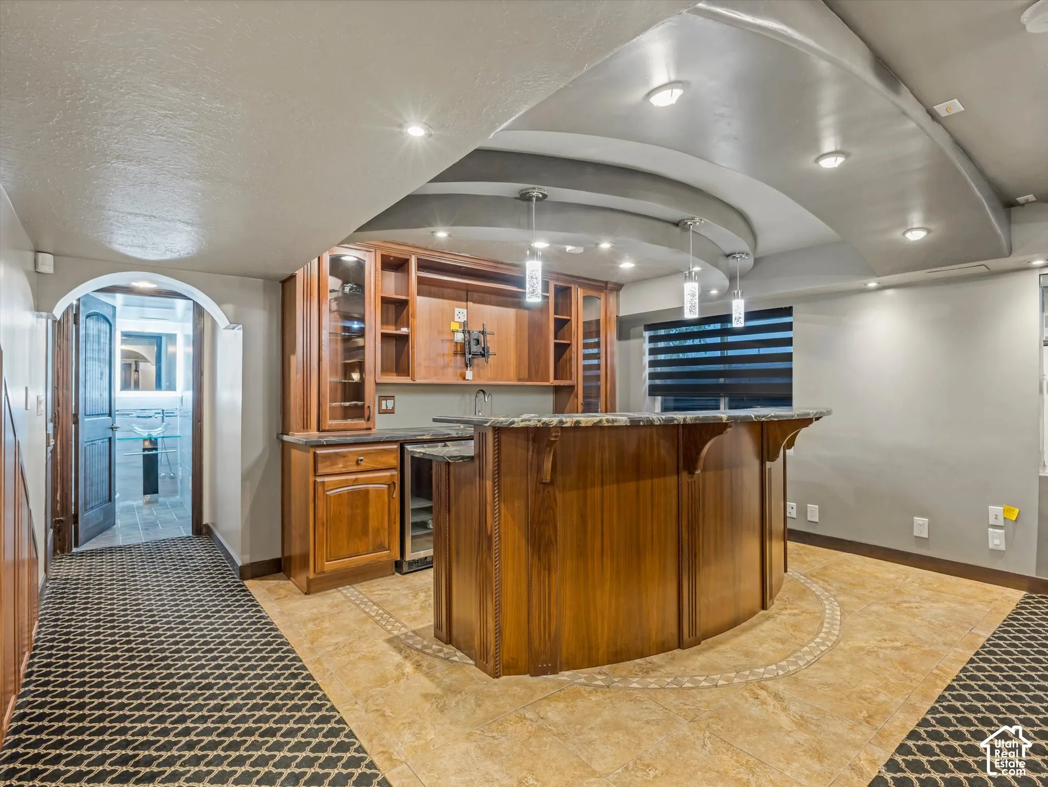 Custom built-in bar with wood cabinetry, integrated beverage refrigerator, and stone countertop