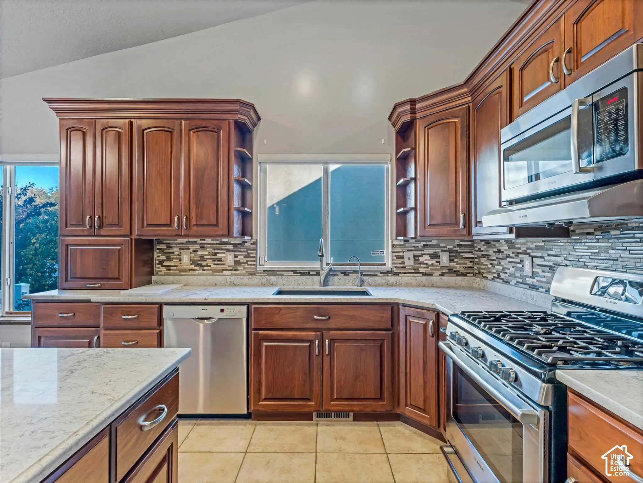 Kitchen featuring wood cabinetry, stainless steel appliances, countertops, and a tiled backsplash