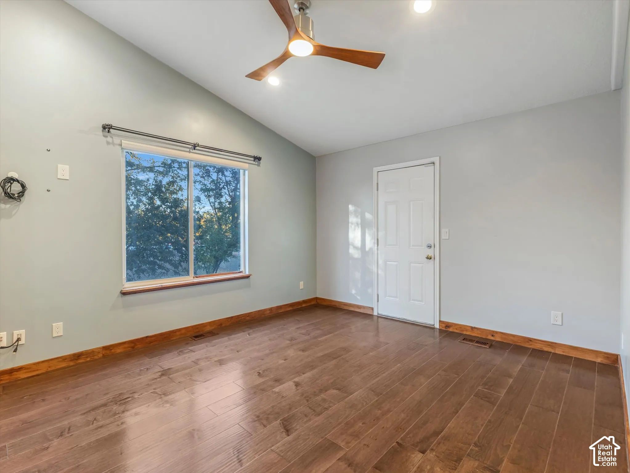 Vaulted ceilings with a ceiling fan, wood-finish flooring, and a window with a wood sill