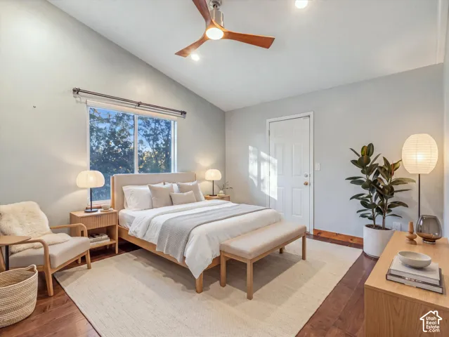 Vaulted ceiling with a wood-finish ceiling fan, wood-finish flooring, and a large window.Digitally Staged.