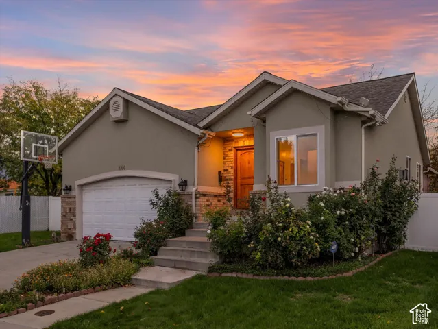 Stucco exterior with stone accents, featuring a prominent front entry, a single-car garage, and established landscaping
