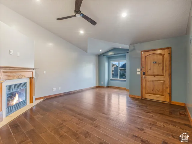 Hardwood flooring, vaulted ceilings, recessed lighting, ceiling fan, and a fireplace with a decorative mantel