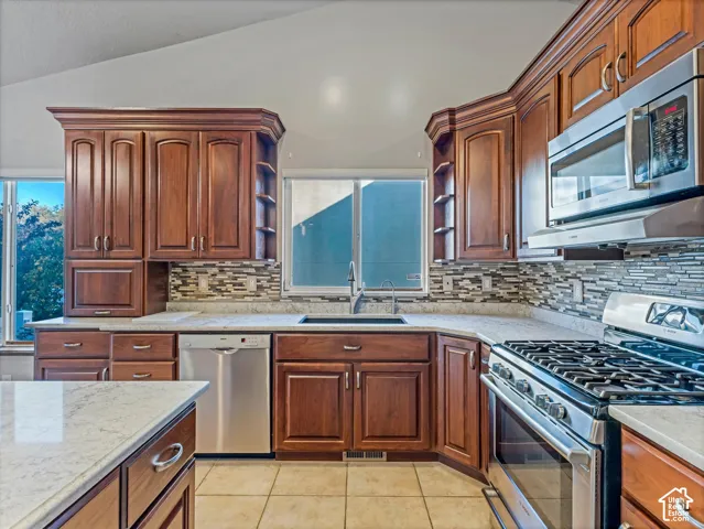 Kitchen featuring wood cabinetry, stainless steel appliances, countertops, and a tiled backsplash