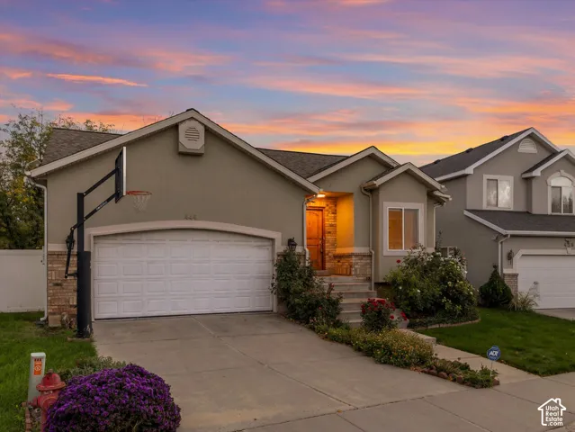 Stucco exterior with stone accents, concrete driveway, and established landscaping