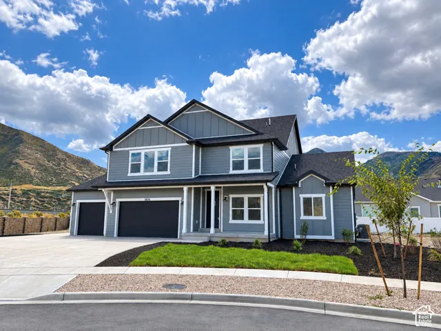 Two-story residence featuring a gray exterior with white trim, a multi-car garage, front yard landscaping, and a paved driveway
