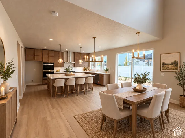 Open-concept living space with wood-finish flooring, a kitchen featuring wood cabinetry and white countertops, a dining area, a kitchen island with seating, and a vaulted ceiling