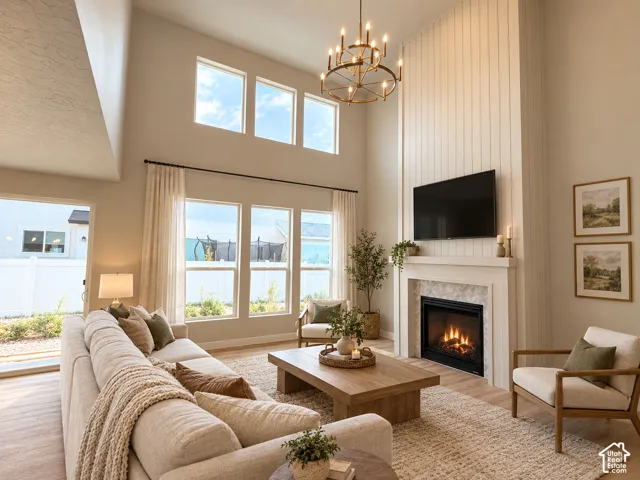 Vaulted ceiling with a chandelier, multiple windows, built-in fireplace with a mantel, television mount, and wood-finish flooring