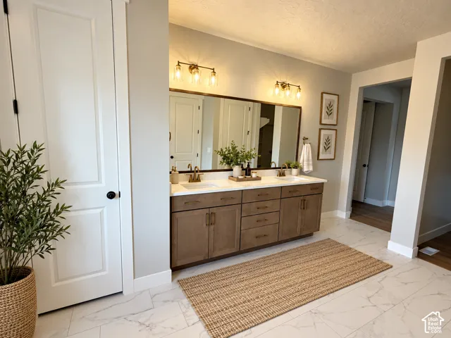 Dual vanity with integrated sinks, wood-finish cabinetry, and brushed brass fixtures