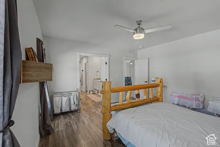 Wood-finish flooring, ceiling fan with integrated lighting, and multiple doorways leading to additional rooms