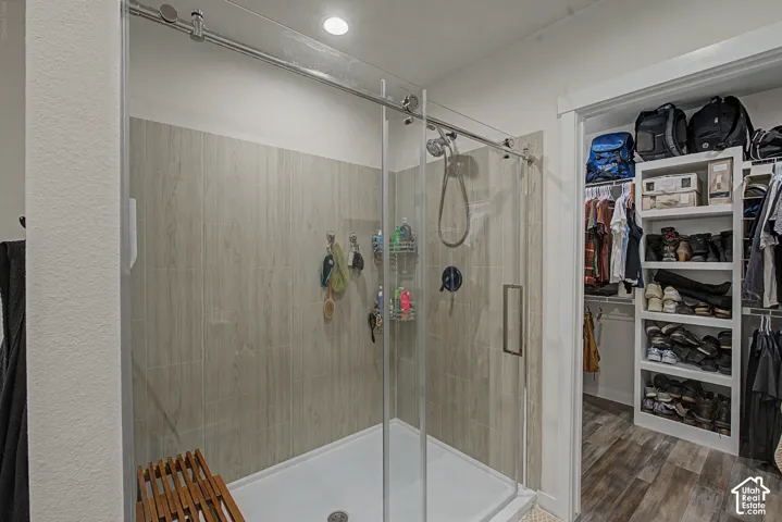 Glass-enclosed shower with wood-finish tile surround and dark-finish fixtures