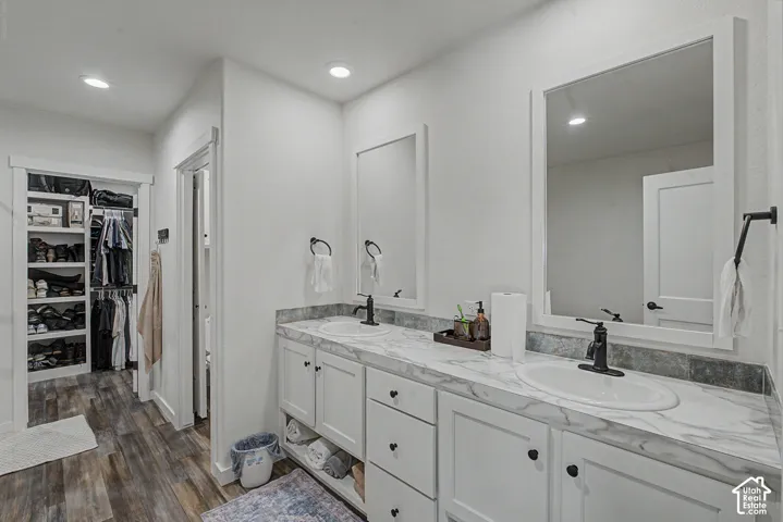 Dual sink vanity with white cabinetry, black fixtures, and framed mirrors
