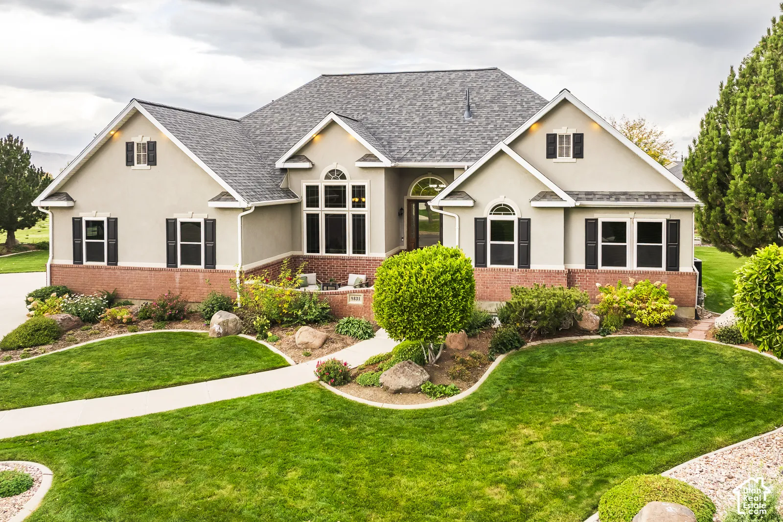 Stucco exterior with brick detailing, arched windows, and a shingled roof