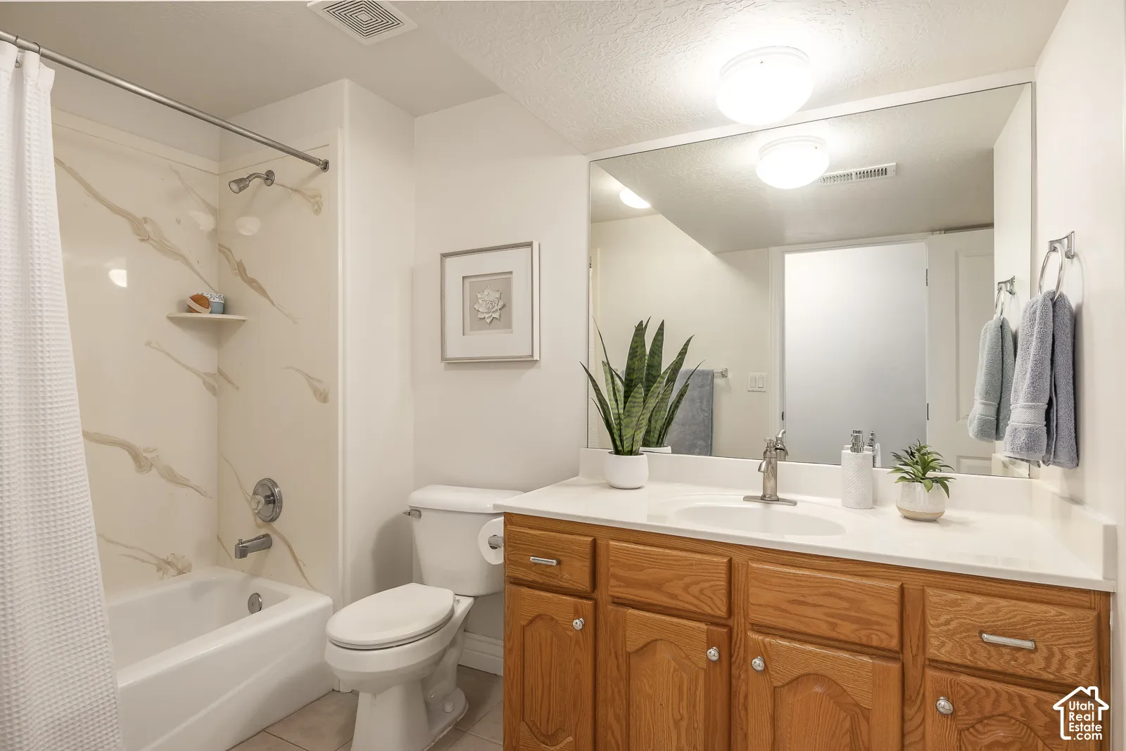 Bathroom featuring a built-in bathtub with shower, wood-finish vanity with countertop, and an integrated sink with a chrome faucet