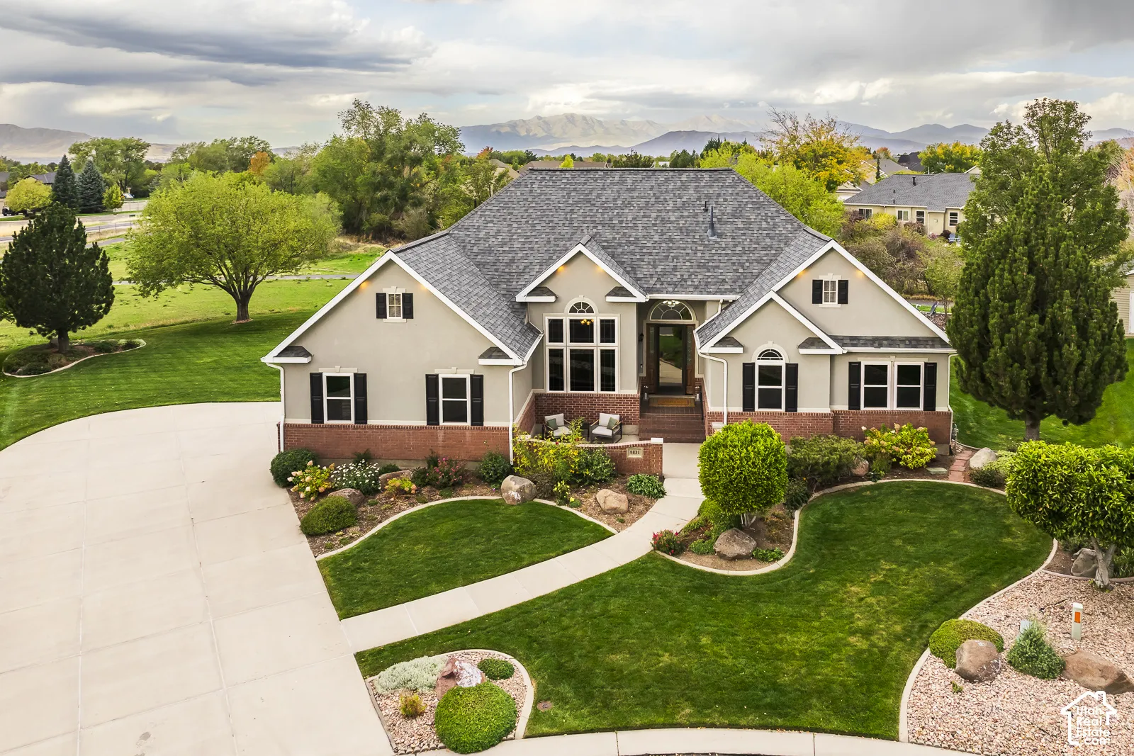 Expansive front yard with a circular driveway, mature trees, and professional landscaping