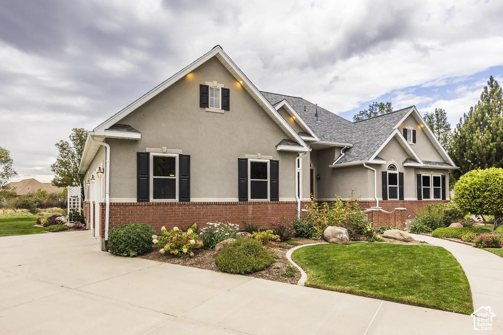 Stucco exterior with brick detailing, multi-pitch roofline, and established landscaping