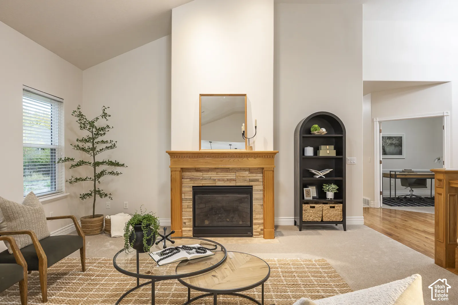 Vaulted ceilings, a fireplace with a wood mantel and stone surround, and carpet flooring