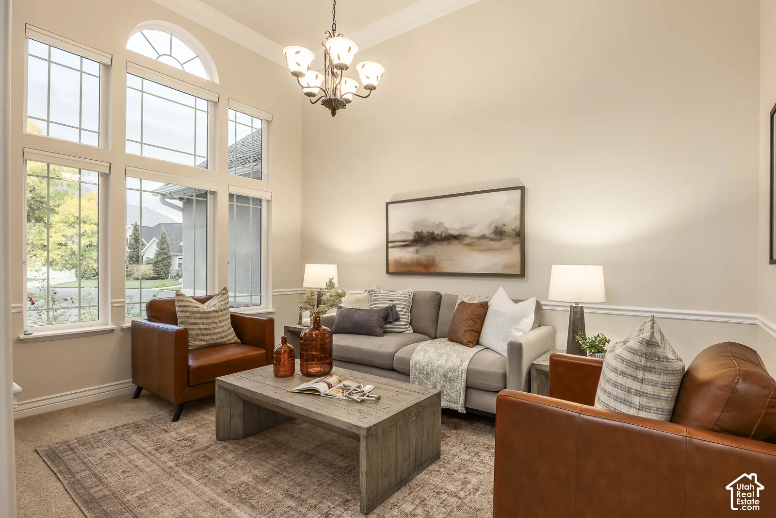 Soaring ceilings with crown molding, a multi-pane arched window, and wainscoting details