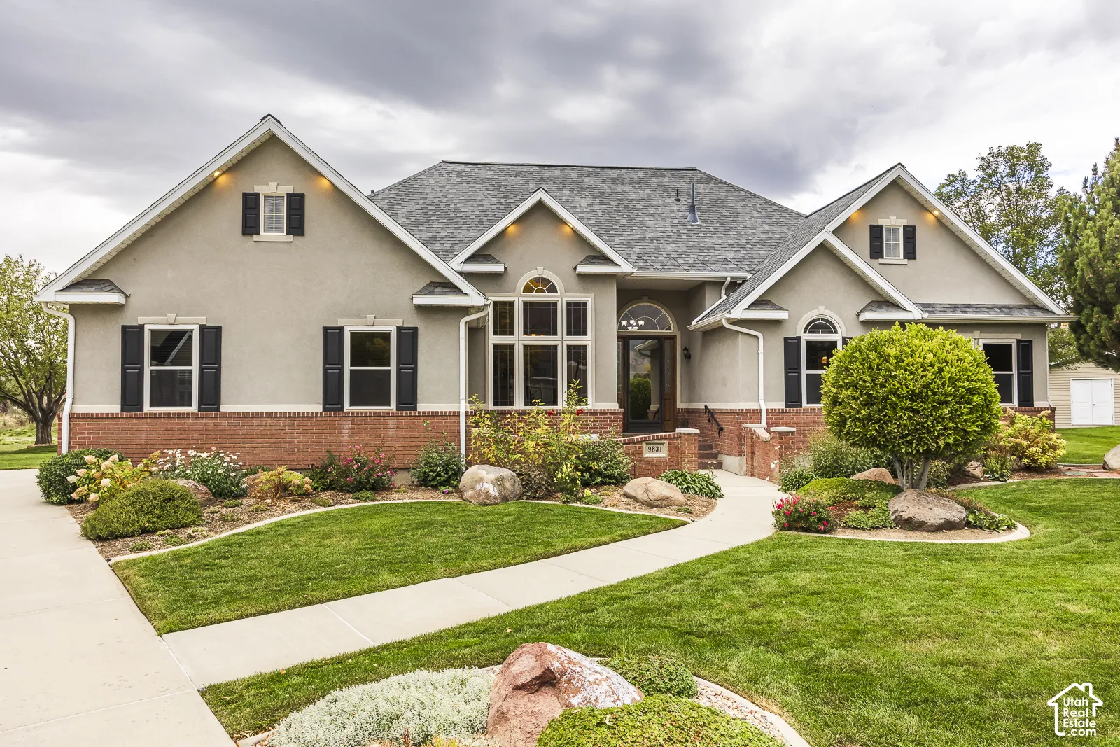 Stucco and brick exterior with a gabled roofline, featuring decorative window shutters and arched entry