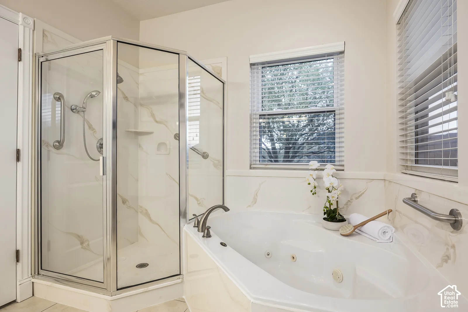 Corner glass-enclosed shower with wall-mounted grab bars and integrated shelving
