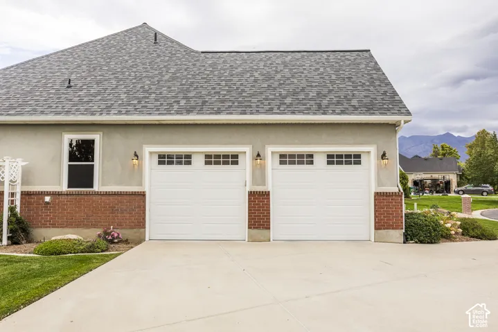 Two-car garage with white paneled doors, decorative windows, and exterior lighting